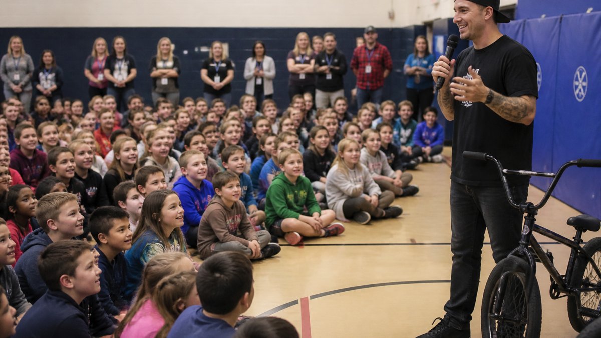 BMX athlete sharing tips on character development with an engaged audience of students at a school assembly.